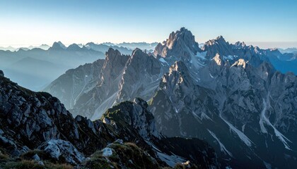 Majestic Mountain Peaks Bathed in Golden Sunlight Under a Clear Blue Sky with Soft Haze in the Distance
