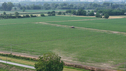 Obraz premium Aerial perspective showcases a dedicated farmer skillfully operating a tractor amidst a vast soybean field meticulously applying essential pesticides for crop protection and enhanced yield