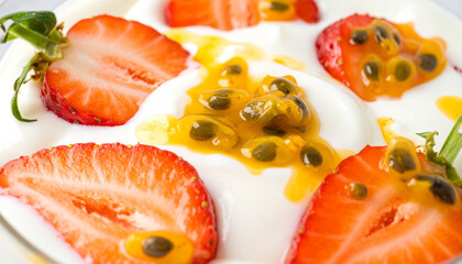 Yogurt with passion fruit pulp and sliced strawberries, macro close-up