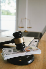 Judge’s gavel placed on money beside legal documents, pen, and laptop, symbolizing law, justice, corruption, or financial judgment.