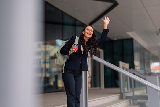 Happy businesswoman waving hand hailing taxi in city