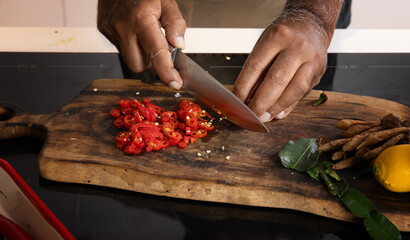 Sliced red chili, fresh herbs, and lemon on rustic wooden cutting board, hands chopping ingredients...