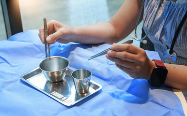 Sterile surgical instrument preparation, healthcare professional with stethoscope, blue drape, stainless steel tray, focused atmosphere