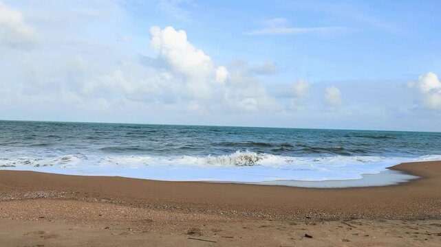Experience the serenity of a tropical beach where gentle waves caress soft sand under a sky filled with drifting clouds. The ocean breeze and distant horizon create a peaceful escape into nature&rsquo;s.