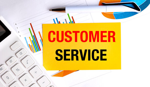 Customer service text on yellow card with charts, calculator and pen on white office desk