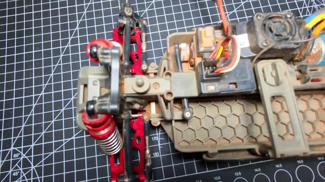 Top-angle footage of testing a toy car's wheel drive servo. Videography of the servo mechanism that drives the wheels to turn left and right. Repair and maintenance of toy hobby RC cars in 4K Footage