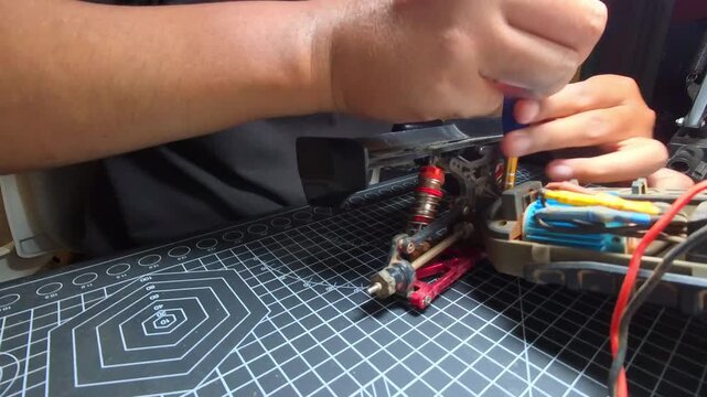 Time-lapse footage of a screwdriver being turned to unscrew a bolt on a remote control car. Videography of repair and maintenance of hobby toys by a mechanic. High-Quality 4K Resolution Footage