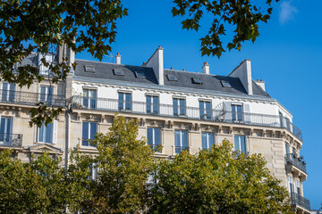 Immeuble résidentiel de style classique parisien vu depuis une avenue bordée d'arbres. Concept de marché immobilier d'habitation pour les logements anciens en France et à Paris