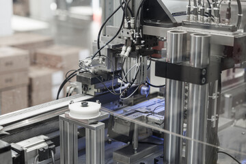 Close-up of an industrial wire processing machine featuring rollers, pneumatic actuators, and numerous cables in a high-tech automation system. Includes copy space