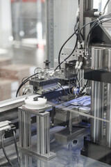 Close-up of an industrial wire processing machine featuring rollers, pneumatic actuators, and numerous cables in a high-tech automation system. Includes copy space