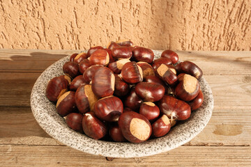 A rustic autumn scene featuring a plate of freshly harvested chestnuts resting on a wooden table in a cozy mountain cabin, evoking warmth, tradition, and the taste of the season