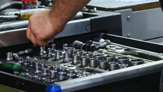 Mechanic hands chooses steel bits for car spanner in toolbox drawer at service station closeup. Employee works with manual tools in garage