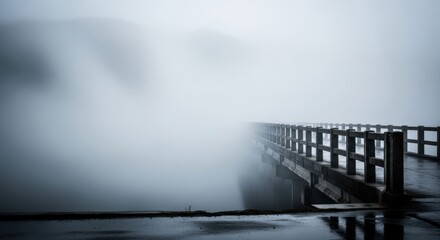 A wooden pedestrian bridge disappears into a thick, swirling fog, with reflections visible on the wet surface, evoking a sense of isolation and mystery