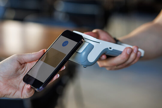 Contactless smartphone payment at POS terminal — tap to pay mobile wallet in retail - Powered by Adobe