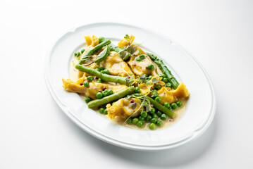 Gourmet stuffed pasta with asparagus, green peas, microgreens, and creamy yellow sauce, elegantly plated on a white dish. Fine dining presentation, top view.