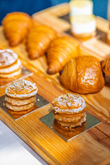 “Assorted artisanal desserts and pastries displayed on wooden table in modern bakery”