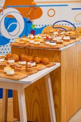 “Assorted artisanal desserts and pastries displayed on wooden table in modern bakery”