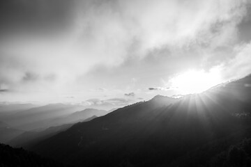 Black and white sunset photo with fog on the sky and hazy mountain range