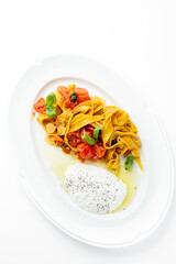 Tagliatelle pasta with cherry tomatoes, garlic, basil, and creamy burrata cheese on a white plate. Gourmet Italian dish with elegant presentation and fresh ingredients.
