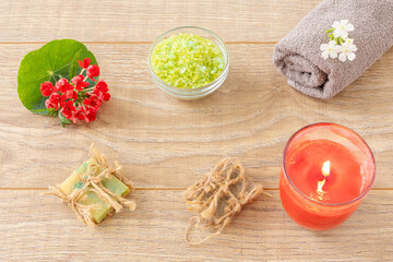 Towel with body care products and verbena flowers on the wooden background.