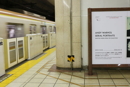 TOKYO, JAPAN - October 18, 2025: Platform of a Tokyo Metro Station with a Yurakucho Line train departing and a billboard advertising an Andy Warhol exhibition at the Espace Louis Vuitton Tokyo.