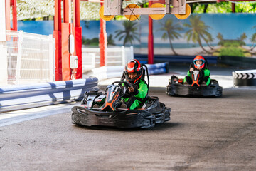 Children wearing helmets and racing suits enjoying a fun competition, racing go karts around an outdoor track