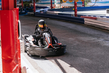 Racer wearing helmet and suit, driving a go kart on an outdoor track, enjoying a fun motorsport activity