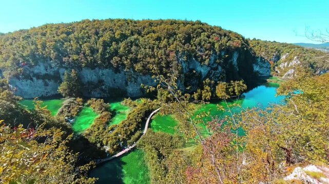 A shot from above of the tuff barrier separating the Plitvice Lakes surrounded by a beautiful, colorful autumn forest.