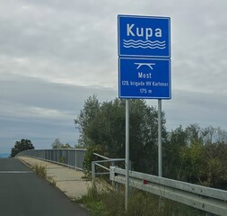 A board with the name of the river at the bridge over the Kupa River in Croatia.