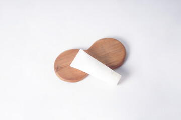 A wooden bowl holds a sunscreen tube on a plain white background.