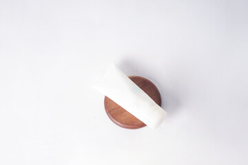 The image shows a sunscreen resting on a wooden container over a white surface.