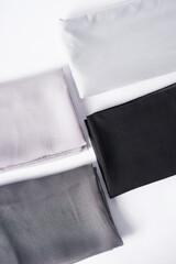 The image shows black, white, and gray scarves neatly arranged on a white surface.