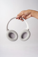 A headset is held by a hand against a white background.