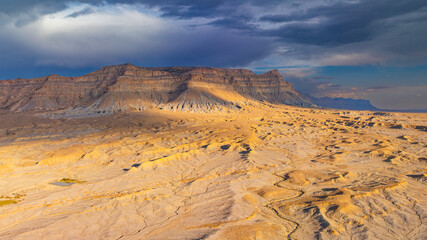 Fototapeta premium Aerial view of barren desert cliffs in Utah. Aerial drone image of rugged barren cliffs and layered mesa in Utah desert landscape.