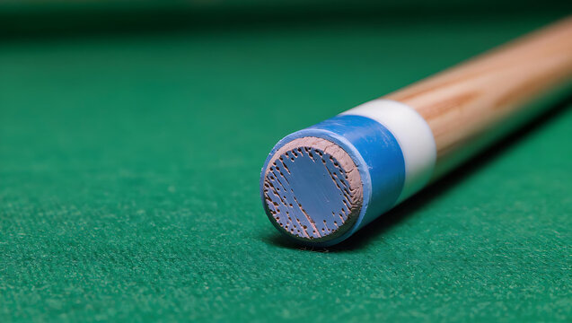 Detail of a pool cue tip and chalk cube on a billiard table.