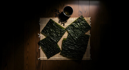 Minimalistic Composition of Nori Seaweed Sheets On Bamboo Mat With A Cup Of Tea