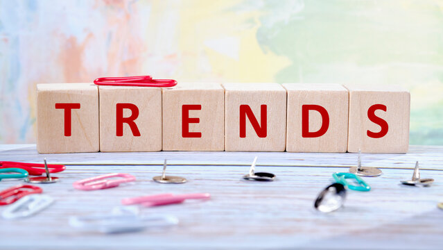 Wooden blocks arranged to spell trends sit prominently on a desk surrounded by colorful paper clips and push pins, creating an inspiring atmosphere for work or study - Powered by Adobe