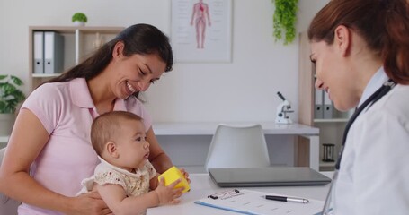 Pediatrician consultation for smiling young mother holding newborn baby. Kids examination by doctor explaining pediatric care, vaccine and medical disease prevention during routine hospital checkup - Powered by Adobe