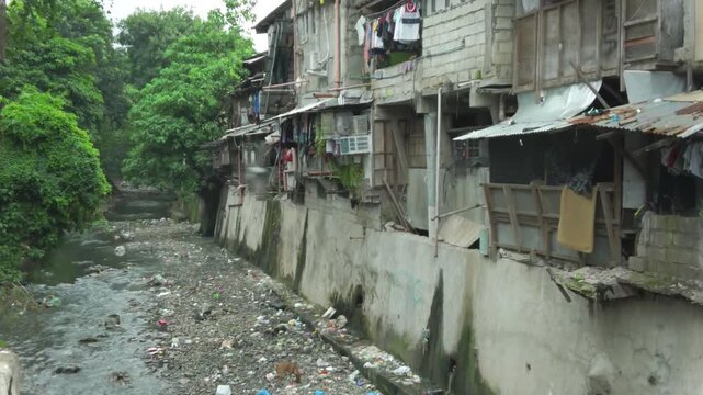 Poor dirty slum area with garbage polluting the creek.