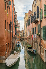 Narrow water canal with moored boats in Venice, Italy