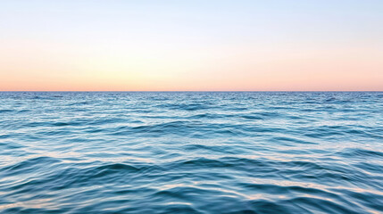 Fototapeta premium Calm blue ocean meets soft pink sky at sunset, creating dreamlike atmosphere