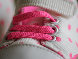 Close-up of newborn baby girl shoes with a pink tint and polka dots.

