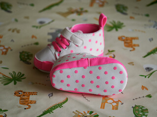Close-up of newborn baby girl shoes with a pink tint and polka dots.
