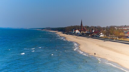 Peaceful seaside town Sarbinowo with calm waves and golden sands from above.