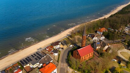 Peaceful seaside view of Sarbinowo under clear sky, gentle Baltic waves touch the shore.
