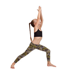 Young girl doing warrior yoga pose in camo leggings and black top on white background.