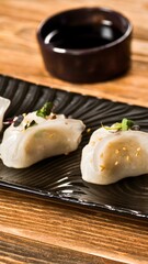 Two pieces of sushi with sesame seeds on a black plate