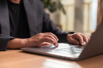 Close-up of man's hands working on laptop at office desk. Represents digital communication, business productivity, remote work, professional technology use, and modern workplace environment.