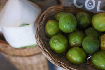 Vibrant green limes artfully arranged within rustic woven basket, providing refreshing and healthy citrus fruit selection. Organic produce, likely found bustling market, evokes wholesome culinary