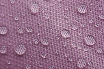 Glistening water droplets bead gracefully purple fabric, highlighting its excellent waterproof resistant properties. textured surface creates captivating display of liquid spheres, evoking feeling